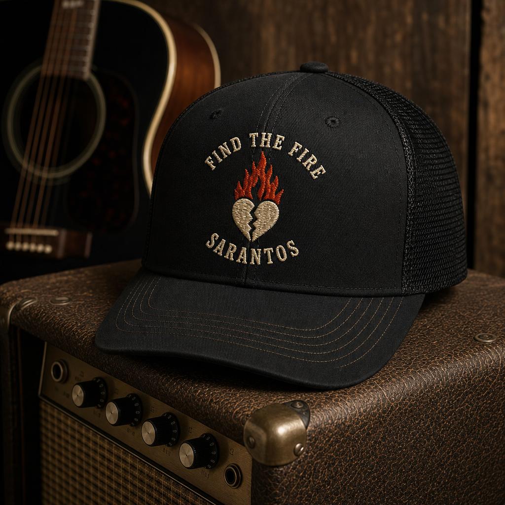 Black trucker hat with embroidered Sarantos "Find The Fire" flame heart design, on an amplifier